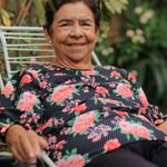 Elderly woman enjoying a peaceful moment outdoors in a garden setting.